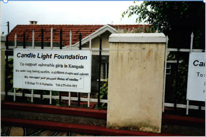 Punatiilikattoinen matala rakennus, jonka edustalla kyltti kertoo rakennuksen olevan kynttilänvalmistuspaja, joka tukee Kampalan haavoittuvassa asemassa olevia tyttöjä.