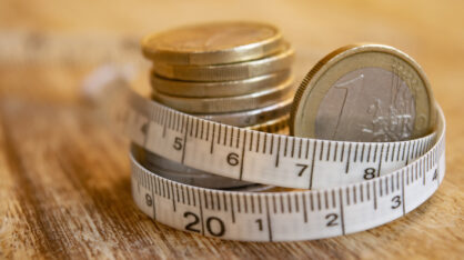 Pile of euro coins with a tape measure around them