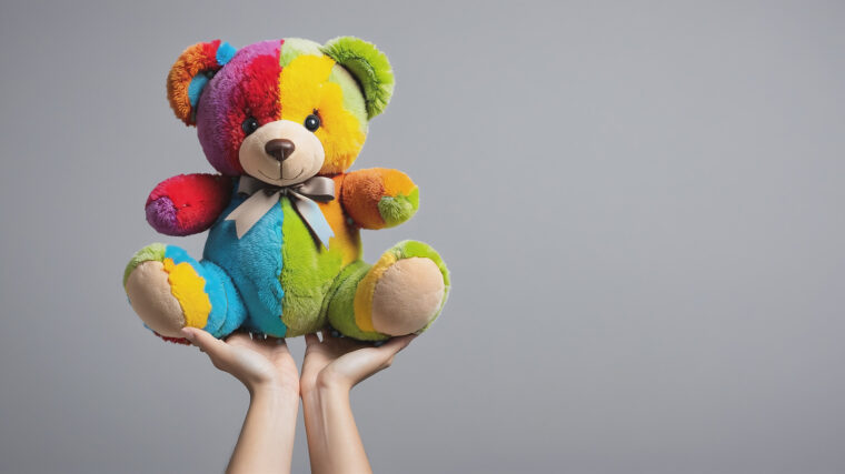 Kaksi kättä pitää eri puolilta pehmolelua, joka edustaa huolenpitoa.