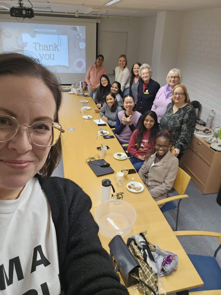 Joukko iloisia ihmisiä soroptimistien tapaamisessa.