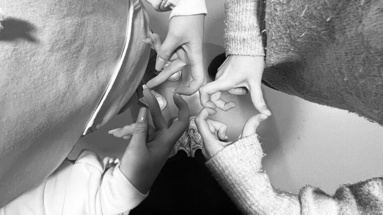 Kolme ihmistä seisoo ympyrässä ja muodostaa käsillään sydämen muotoisen kuvion.