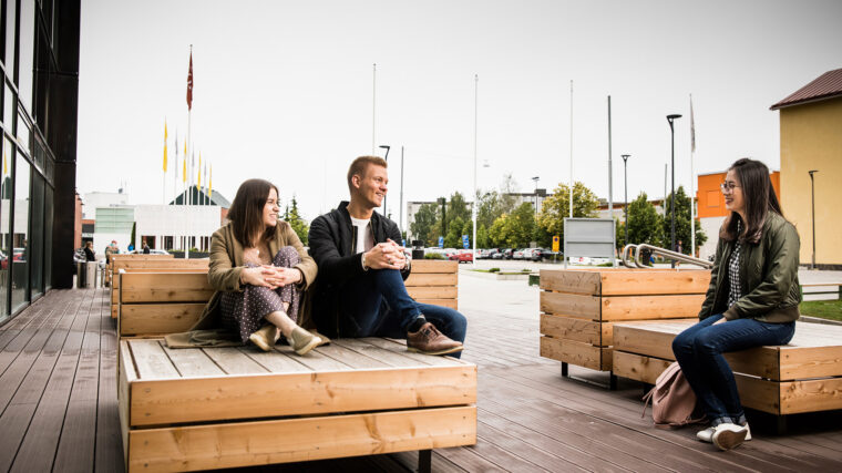 Opiskelijoita rennosti juttelemassa korkeakoulun edessä.