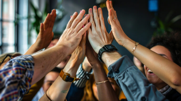 Työtiimi lyö kädet yhteen.