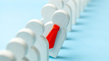 Monta puista ukkelia rivissä, yksi erottuu joukosta punaisessa kravatissa.