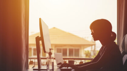 Nainen tekee töitä kotona tietokoneen ääressä.